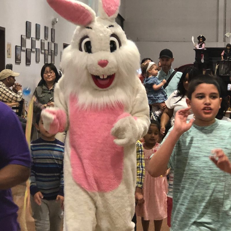 a group of people standing next to a stuffed animal