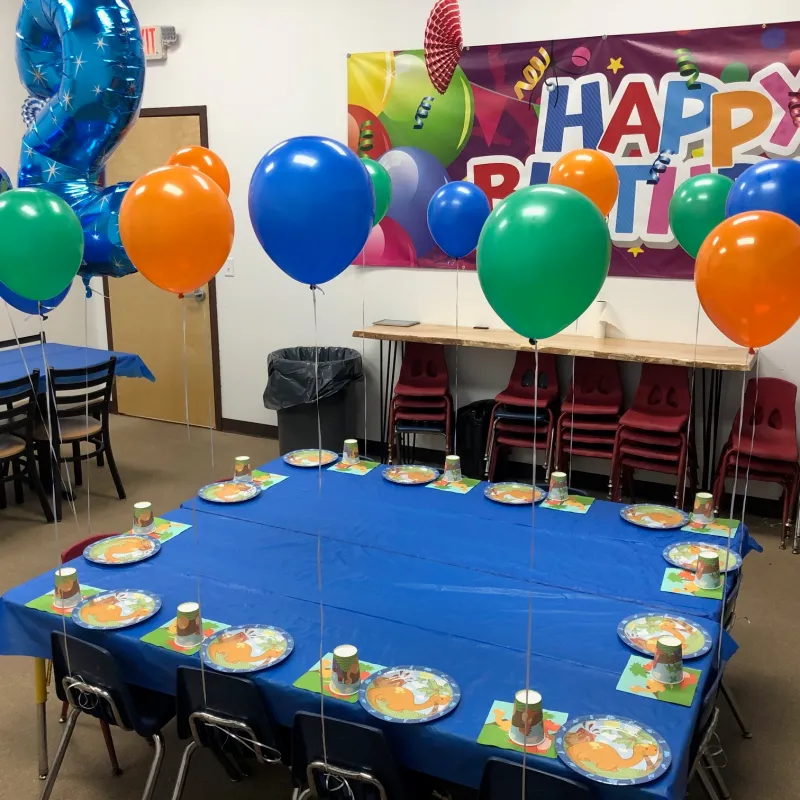 a group of people sitting at a table with a blue umbrella