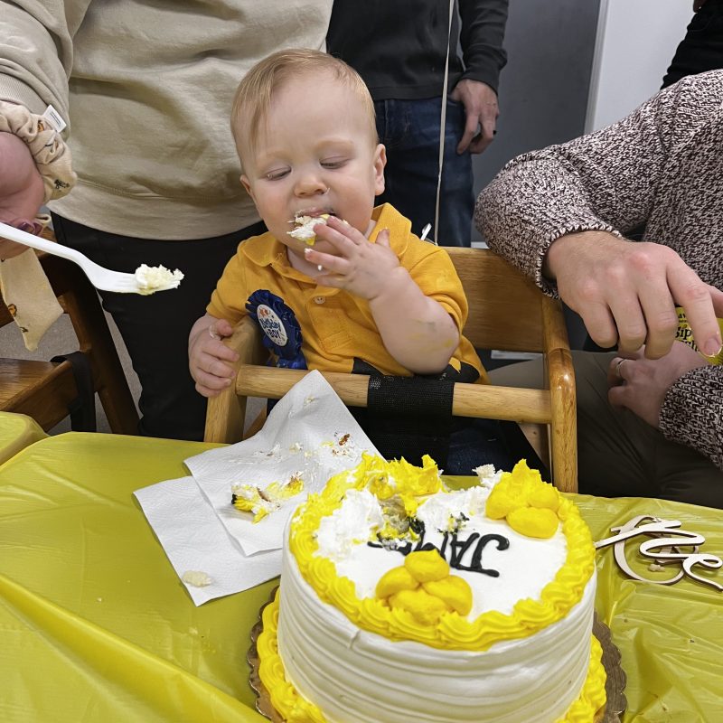 a group of people sitting at a table with a cake