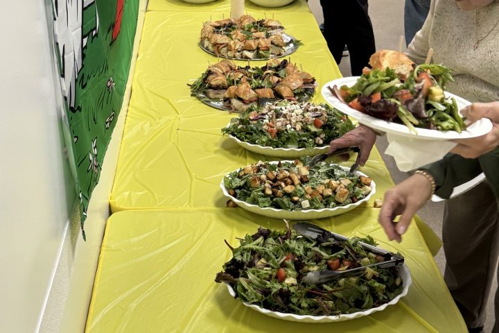 a group of people standing around a table with food