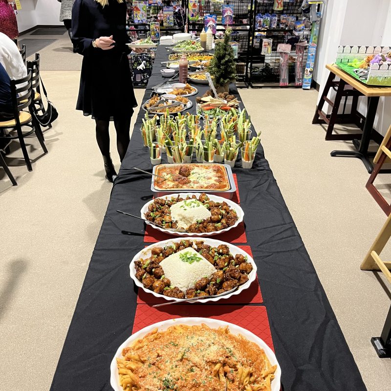 a group of people standing around a table with a plate of food
